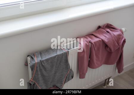 Die Kleidung hing auf dem weißen Heizkörper im Zimmer Stockfoto