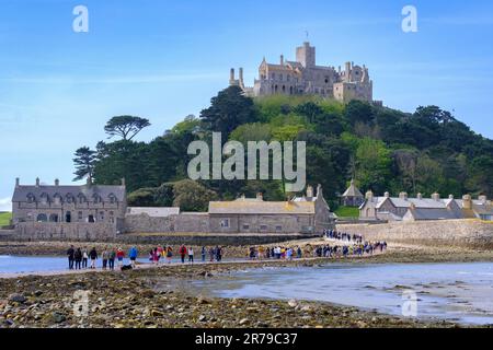 Menschen gehen bei Ebbe auf dem Damm zum St. Michael's Mount, Mount’s Bay, Marazion, Cornwall, England, UK. Stockfoto