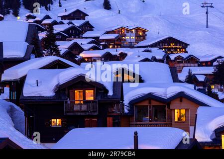 Hölzerne Chalets mit tiefem Schnee in der kalten Wintersaison zu den Blue Hours in der Alpenregion Stockfoto