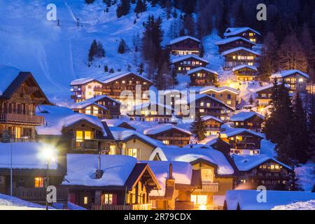 Hölzerne Chalets mit tiefem Schnee in der kalten Wintersaison zu den Blue Hours in der Alpenregion Stockfoto