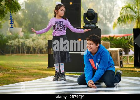 Neu-Delhi, Indien - 10.12.2022 - Kinder tanzen auf der Tanzfläche zu Musik auf der Outdoor-Kinderparty, lustige glückliche Kinder tanzen auf der Outdoor-Kinderparty Stockfoto