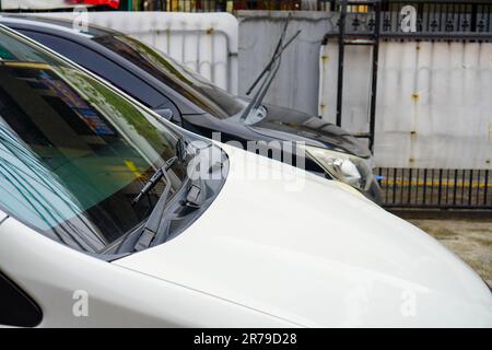 Selektiver Fokus auf geparkte weiße und schwarze Fahrzeuge mit Wischerblättern nach oben Stockfoto