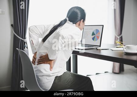 Junge Asiatin sitzt auf der Arbeit und hat Spannungsschmerzen im Nacken. Concept-Office-Syndrom Rückenschmerzen von Berufskrankheiten, weiblich haben Stockfoto