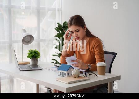 Asiatischer Buchhalter, der Haushaltsrechnungen berechnet, Haushaltsrechnungen prüft und analysiert und Steuererklärungen einreicht Stockfoto