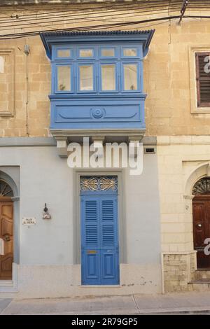 Alte Hausfassade mit blauer Tür und einem traditionellen geschlossenen blauen Holzbalkon (Gallarija) in Paola, Malta Stockfoto