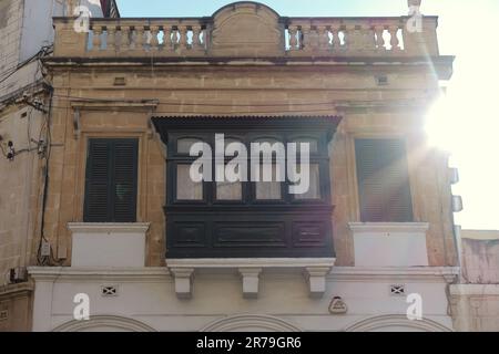 Alte Palastfassade mit traditionellem geschlossenen Holzbalkon (Gallarija) und zwei seitlichen Fenstern in Paola, Malta Stockfoto