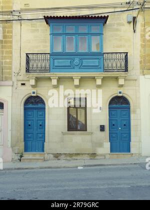 Äußeres altes Haus mit zwei Vordertüren, einem Fenster und einem traditionellen geschlossenen Holzbalkon (Gallarija) in Paola, Malta Stockfoto
