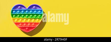 POPIT - farbenfrohes Anti-Stress-Sinnesspielzeug für Kinder. Neues beliebtes Silikonspielzeug – auf gelbem Hintergrund anbringen. Regenbogenfarbe. Draufsicht Kopierbereich. Trend o Stockfoto
