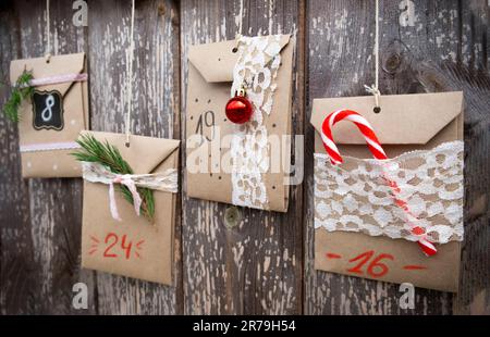 Adventskalender Für Weihnachten. Süßigkeiten versteckt in Papiertüten, die auf Holzhintergrund hängen. Saisonale Aktivität für Kinder, Familienurlaub im Winter. Handgemachter Tink Stockfoto