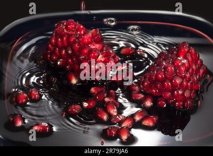 Saftige Granatapfelsamen im eigenen Saft. Nahaufnahme vor einem dunklen Hintergrund Stockfoto