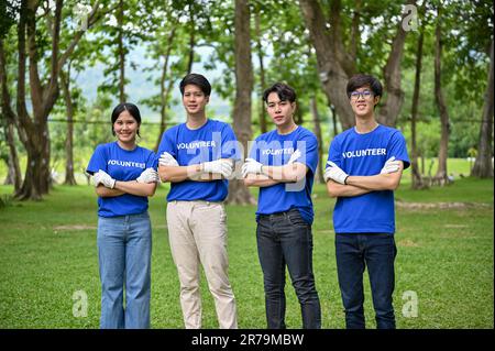 Eine Gruppe glücklicher, junger asiatischer Freiwilliger in Uniform, die im öffentlichen Park mit verschränkten Armen standen und in die Kamera blickten. Freiwilligenarbeit, Team, Stockfoto