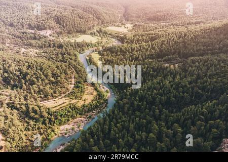 Luftaufnahme des azurblauen gewundenen Flusses in einem tiefen Canyon, umgeben von ruhigen Wäldern Stockfoto