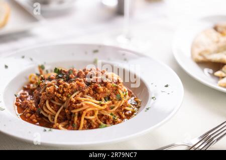 Spaghetti mit Hackfleisch im Bolognesstil serviert auf einem Teller mit frischen Kräutern. Stockfoto