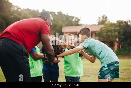 Schulsportmannschaft, die sich auf einem Rugby-Feld tummelt. Der Trainer hält seinen Schülern vor dem Üben einen motivierenden Vortrag. Sporttrainer Mentoring Kind Stockfoto