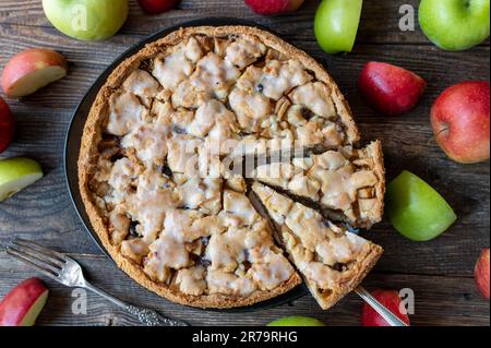 Ganzer und runder Apfelkuchen, gebacken mit kurzer Kruste, vorgekochten Äpfeln, Zimt und Rosinen. Garniert mit einer köstlichen Zitronenglasur Stockfoto