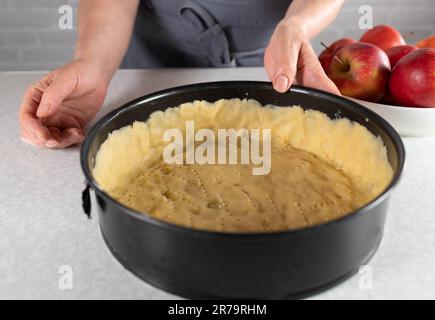 Apfelkuchen mit kurzer Kruste in einer runden Backform zubereiten. Teil einer Serie Stockfoto