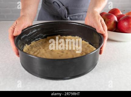 Apfelkuchen mit kurzer Kruste in einer runden Backform zubereiten. Teil einer Serie Stockfoto