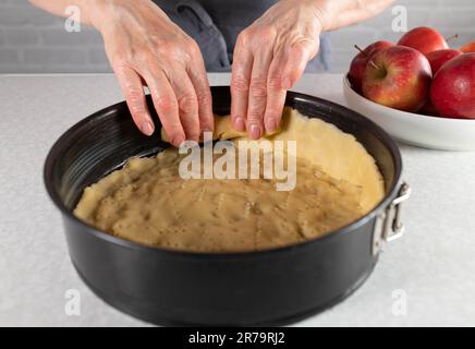 Apfelkuchen mit kurzer Kruste in einer runden Backform zubereiten. Teil einer Serie Stockfoto