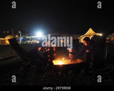 Campingkinder. Kinder, die am Lagerfeuer sitzen und nachts auf dem Campingplatz Marshmallow rösten. Stockfoto