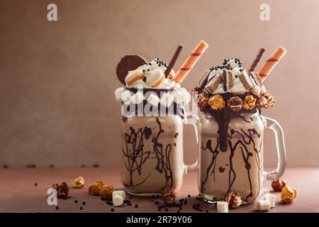 Schokoladenmilchshake mit Eiscreme und mit Schlagsahne, Marshmallow, süßem Popcorn, Keksen, Waffeln, Serviert in einem Glasbecher. „Freak or Crazy“ Stockfoto