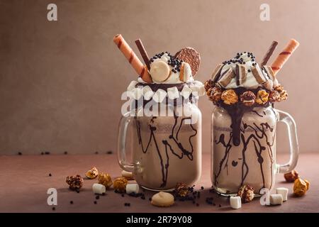 Schokoladenmilchshake mit Eiscreme und mit Schlagsahne, Marshmallow, süßem Popcorn, Keksen, Waffeln, Serviert in einem Glasbecher. „Freak or Crazy“ Stockfoto