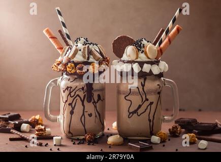 Schokoladenmilchshake mit Eiscreme und mit Schlagsahne, Marshmallow, süßem Popcorn, Keksen, Waffeln, Serviert in einem Glasbecher. „Freak or Crazy“ Stockfoto