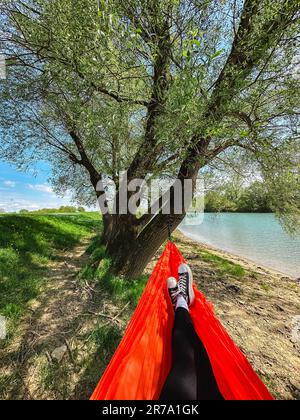 Eine Frau liegt in einer Hängematte am Flussufer Stockfoto