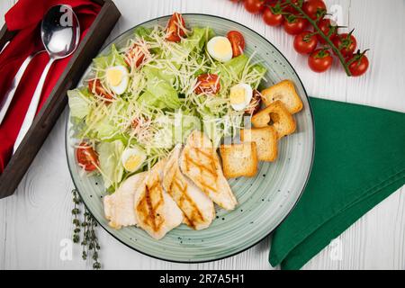 Eine weiße Keramikplatte mit einem frischen grünen Salat garniert mit Tomaten, Gurken und Oliven, begleitet von ein paar Scheiben goldbrauner Kruste Stockfoto