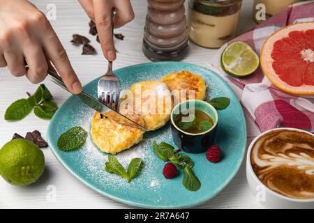 Nahaufnahme einer horizontalen Aufnahme einer weiblichen Hand, die in einen Teller mit Speisen mit einer Vielzahl an Tees, Früchten und anderen Artikeln schneidet Stockfoto