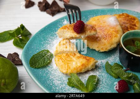 Nahaufnahme eines Tellers mit einem Stapel frisch zubereiteter Pfannkuchen, garniert mit einer Auswahl reifer Beeren und einem Zweig garniert Stockfoto