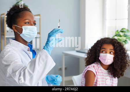 Afroamerikanische Ärztin bereitet Spritze mit Impfstoff für die Immunisierung von Mädchen im Teenageralter vor. Stockfoto