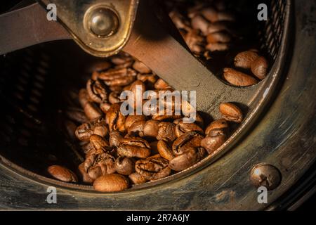 Nahaufnahme von Kaffeebohnen, die in der Trommel einer Rösterei geröstet werden. Stockfoto