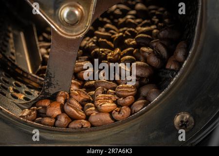 Nahaufnahme von Kaffeebohnen, die in der Trommel einer Rösterei geröstet werden. Stockfoto