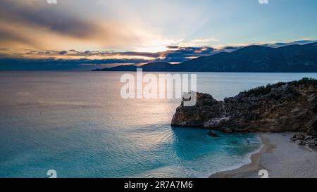 Der Strand von Agiofili bietet ein ruhiges Gewässer, beleuchtet von einem atemberaubenden Sonnenuntergang auf der griechischen Insel Lefkada Stockfoto