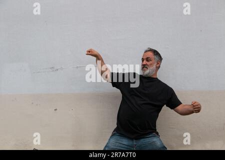 Erwachsener Mann mit Bart und Bauch, schwarzes T-Shirt, das auf das Kopierfeld zeigt Stockfoto
