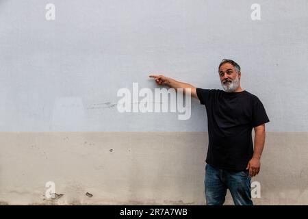 Erwachsener Mann mit Bart und Bauch, schwarzes T-Shirt, das auf das Kopierfeld zeigt Stockfoto