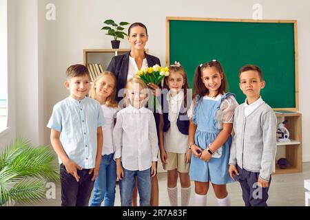 Süße, glückliche kleine Kinder Jungen und Mädchen zusammen mit einer Lehrerin aus der Grundschule Stockfoto