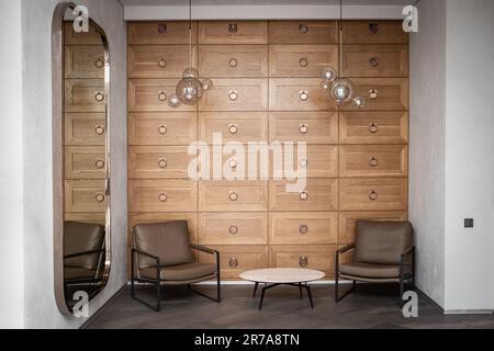 Modernes Interieur im Wartebereich in einem Mini-Hotel mit Couchtisch und zwei Sesseln, Innenausstattung der Hostel-Lobby Stockfoto