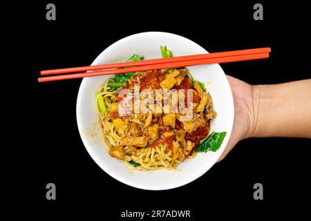 Hähnchennudeln (Mie Ayam) auf schwarzem Hintergrund. Traditionelles indonesisches Essen Stockfoto