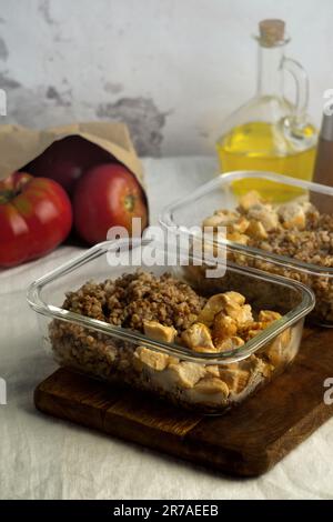 Zwei Kunststoffbehälter gefüllt mit frisch gepflückten roten und grünen Äpfeln auf einem Holztisch in einer hellen und luftigen Küche Stockfoto