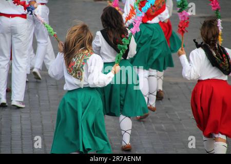 Eine vielfältige Gruppe junger Frauen, die fröhlich in einem Kreis auf der Straße tanzen und einen Moment der Freude und Einheit feiern Stockfoto