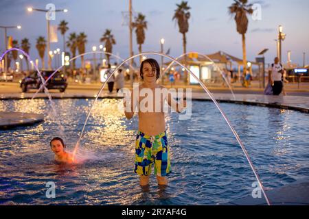 Süßes Kind, Junge, spielt mit Wasser im Brunnen in Tel Aviv, Lichter und Farben Stockfoto