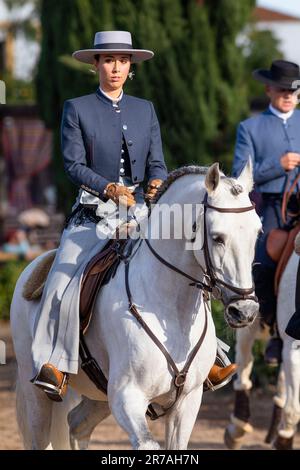 Europa, Portugal, Alentejo Region, Golega, Frau reitet weißes Lusitano Pferd und trägt traditionelles Kostüm auf der Golega Horse Fair 2022 Stockfoto