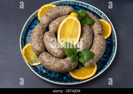 Ein Teller mit Würstchen und Zitronenscheiben garniert mit frischen Minzblättern Stockfoto