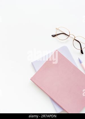 Zwei bunte Notizbücher, Stift und Brille auf weißem Hintergrund. Geschäft, Arbeitskonzept, Blog. Flach verlegt. Speicherplatz kopieren Stockfoto