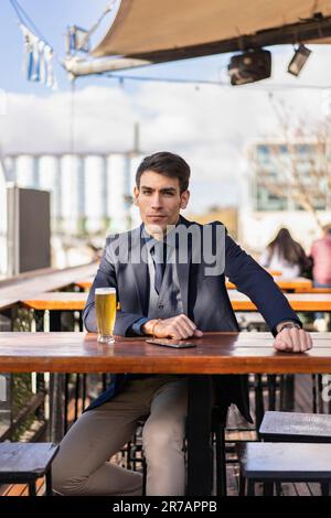 Attraktiver Geschäftsmann, der in die Kamera schaut, während er sein Smartphone hält Stockfoto