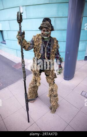 HARROGATE, GROSSBRITANNIEN - 3. JUNI 2023. Ein männlicher Cosplayer, gekleidet als gruselige Vogelscheuche oder Kreatur auf Stelzen, mit einem Sythe bei einem britischen Comic-Trick Stockfoto