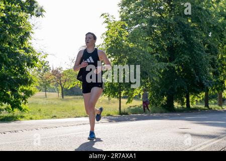 London UK. 13. Juni 2023 Eine Frau, die an einem sonnigen Sommertag im Greenwich Park, London, England bergauf läuft. Kredit: Glosszoom/Alamy Live News Stockfoto