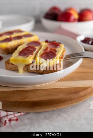 Offen gegrilltes Käsesandwich mit Brie und spanischer Salami. Serviert mit Preiselbeersoße Stockfoto