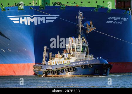 Der Svitzer Marine Hafen Schlepper Svitzer Bargate steht neben einem Ultra Large Container Carrier im Hafen von Southampton Stockfoto